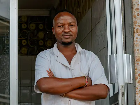 A butcher in a white coat standing in his shop doorway