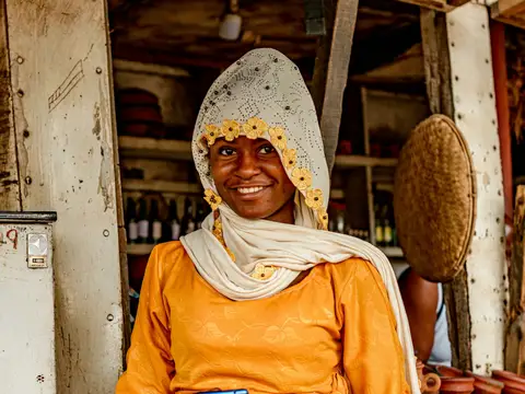 A woman at her fruit stall holding a phone